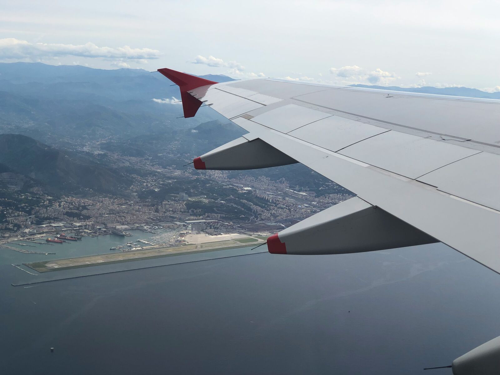 View from an airplane wing flying over the Italian coastline