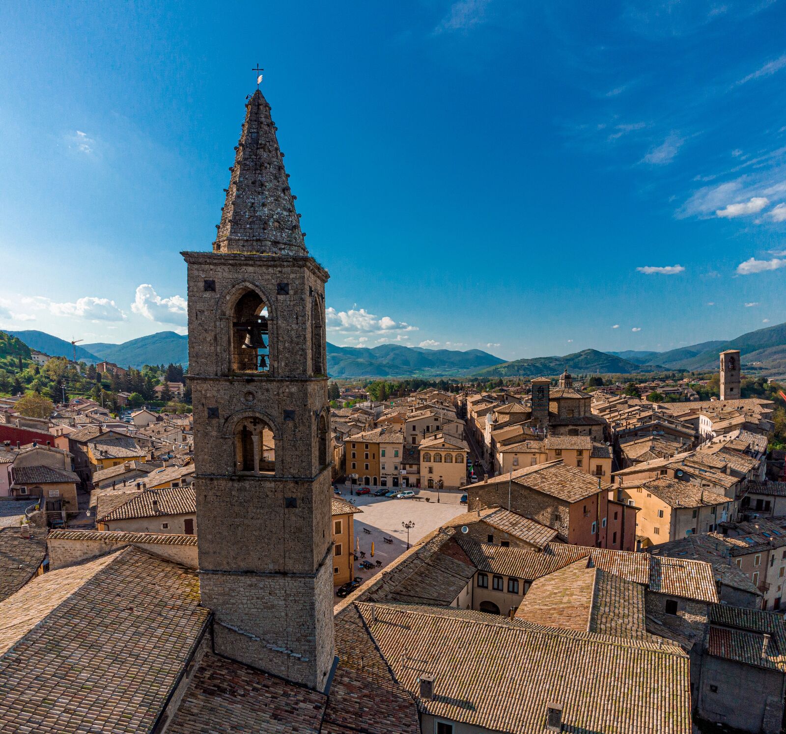 A stone bell tower overlooking the rooftops of a historic Tuscan town